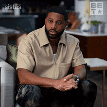 a man sits on a couch in front of a sistas ad