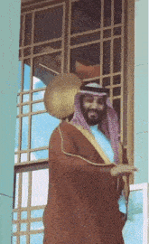 a man in a traditional arabic outfit is standing in front of a window .