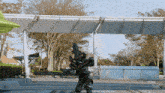 a person in a monster costume is standing in front of a building with trees in the background