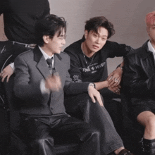 a man wearing a sweater that says hiver sits next to a man in a suit