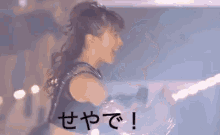 a girl with her arms outstretched is smiling in front of a sign that says " i love you "