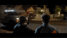 two men are standing next to each other in front of a house .