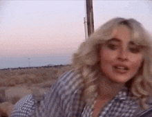 a blonde woman wearing a plaid shirt is smiling