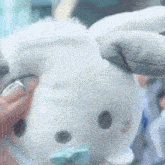 a person holding a stuffed animal with a blue bow tie