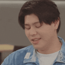 a close up of a man 's face with his eyes closed wearing a denim jacket