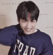 a young man wearing headphones and a blue sweatshirt is laughing .
