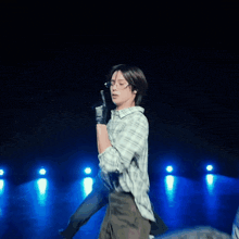 a man wearing glasses and a plaid shirt is holding a microphone