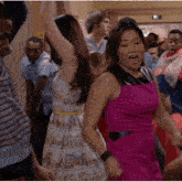 a girl in a pink dress is dancing in a crowd