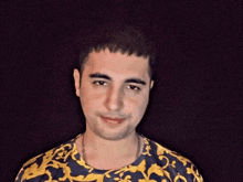 a young man wearing a blue and yellow shirt with a chain around his neck