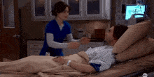 a man is laying in a hospital bed with a nurse standing next to him