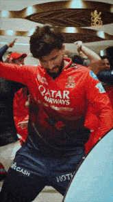 a man wearing a red qatar airways jersey