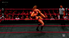 a man is wrestling another man in a wrestling ring while a referee watches .