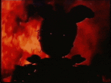 a silhouette of a rabbit with a bow tie is standing in front of a fire .