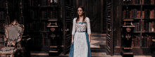a woman in a white and blue dress is standing in a library