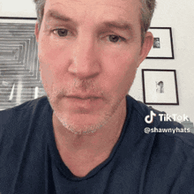 a man with a beard and a blue shirt has a tiktok sticker on his face