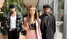 a group of people are walking down a hallway next to a plant .