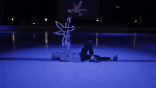 a person laying on a ice rink holding a snowflake