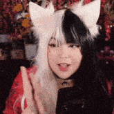 a woman wearing a black and white wig with cat ears is talking on a cell phone .