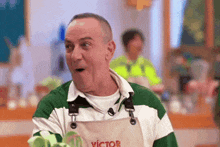 a man wearing an apron that says victor is making a surprised face