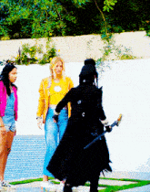 a woman in a yellow crop top is standing next to two other women