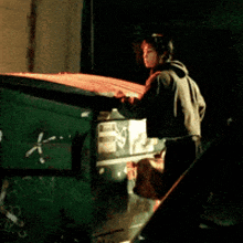 a man standing next to a green dumpster with the letter k written on the side
