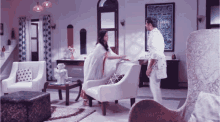 a man and woman are standing in a living room with white furniture