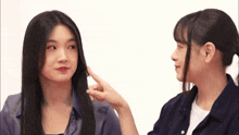 two women are looking at each other and one is pointing at the other 's face