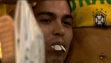 a man with a cbf shirt on his head holds a white object in his mouth