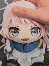 a person holds a stuffed doll with pink hair and blue eyes
