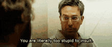a man with glasses is talking to another man and says you are literally too stupid to insult .