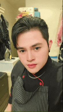 a man wearing a black shirt and striped apron is taking a selfie