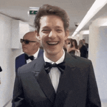 a man in a tuxedo and bow tie is laughing