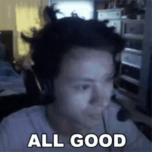 a man wearing headphones says all good in front of a computer screen