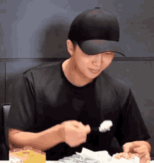 a man wearing a black hat and a black shirt is eating