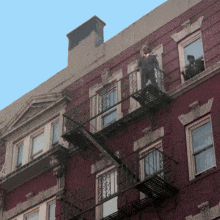 a man in a suit is standing on a fire escape