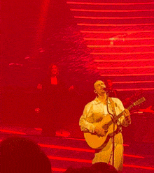 a man playing a guitar on a stage in front of a crowd