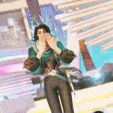 a woman in a green jacket and black pants is standing in front of a building covering her mouth with her hands .