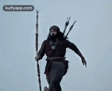 a man with a beard is holding a bow and arrow while flying through the air .