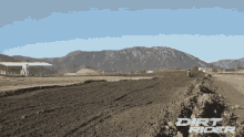 dirt rider is written on a dirt road with mountains in the background
