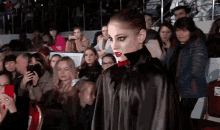 a woman in a black cape is walking in front of a crowd