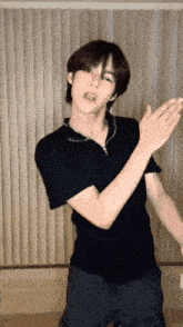 a young man wearing a black shirt is dancing in front of a window .