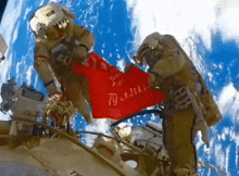 two astronauts in space holding a red flag that says 79 on it