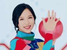 a woman in a colorful sweater is holding a red ball and smiling