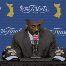 a man sitting at a table with a microphone and the words what 's there to be happy about in front of him