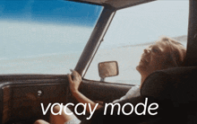 a woman is sitting in a car with the words vacay mode behind her