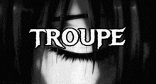 a black and white photo of a woman 's eye with the word troupe in white letters