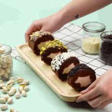 a person is holding a wooden tray filled with chocolate rolls