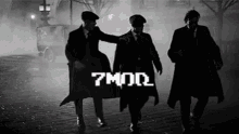 a black and white photo of three men walking down a street with the words 7 mq on the bottom left