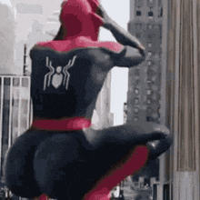 a man in a spiderman costume is standing on top of a building .