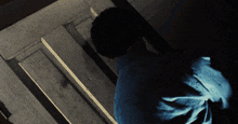 a man in a blue shirt is standing in a dark room